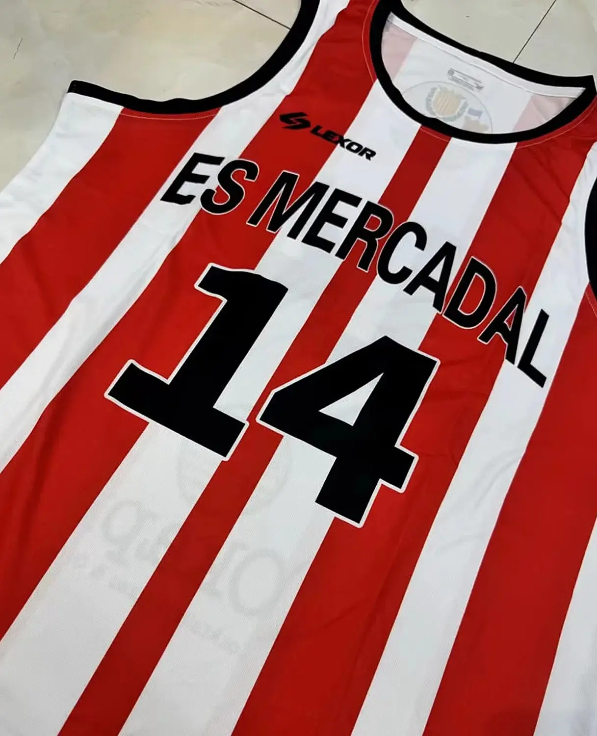 Equipació de bàsquet de ratlles vermelles i blanques d'Es Mercadal amb número i patrocinadors